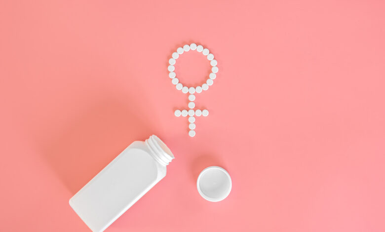 Pills on a pink background, flat lay, women's health.