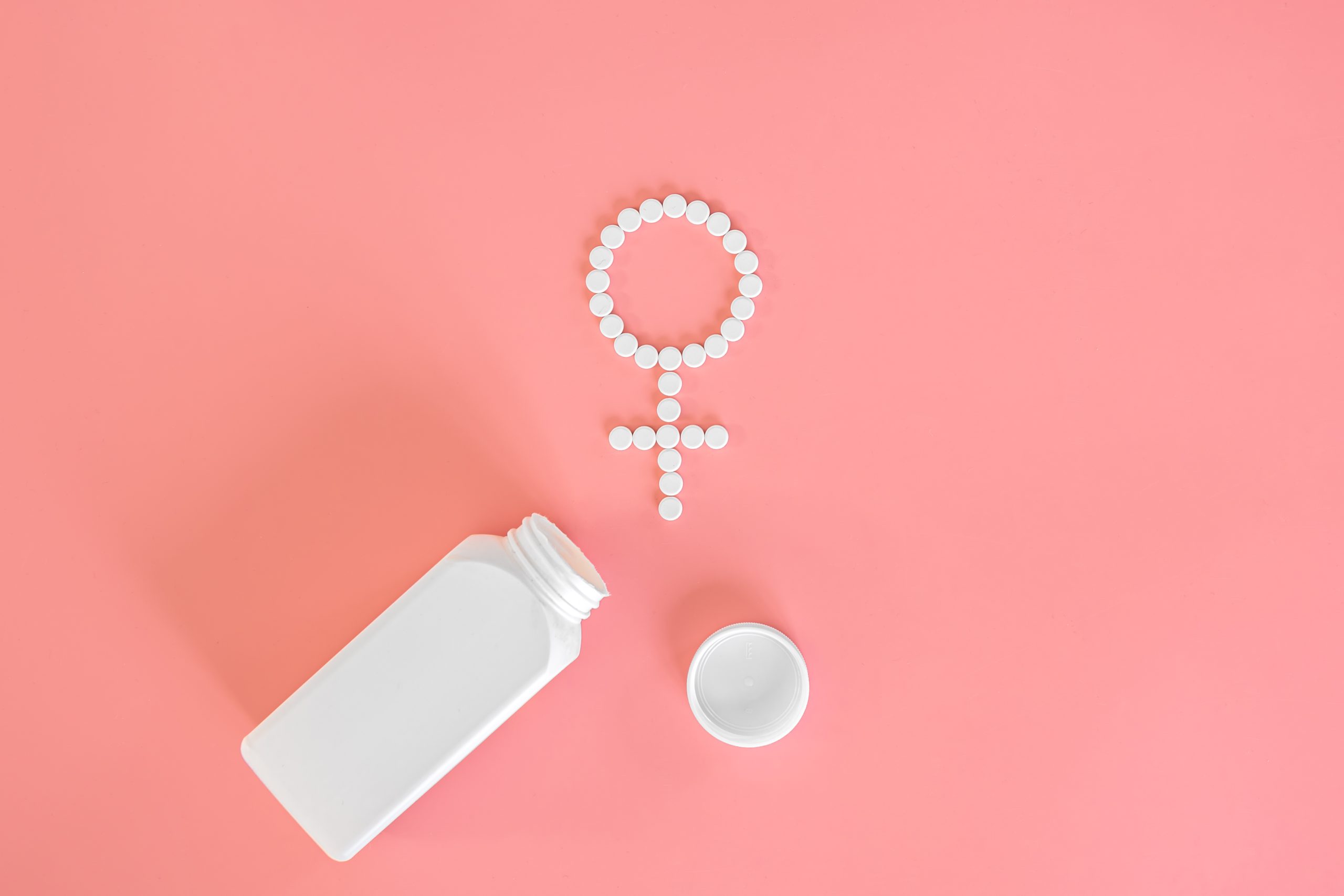 Pills on a pink background, flat lay, women's health.