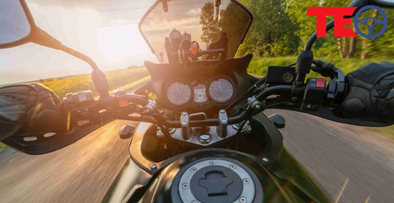 Man driving his motorcycle on asphalt country road. Summer sunset