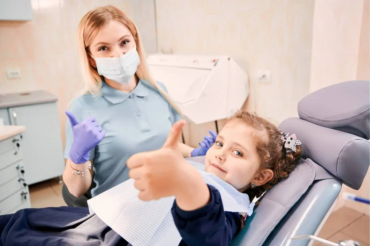 female dentist cute little girl giving thumbs up1 wp jpg